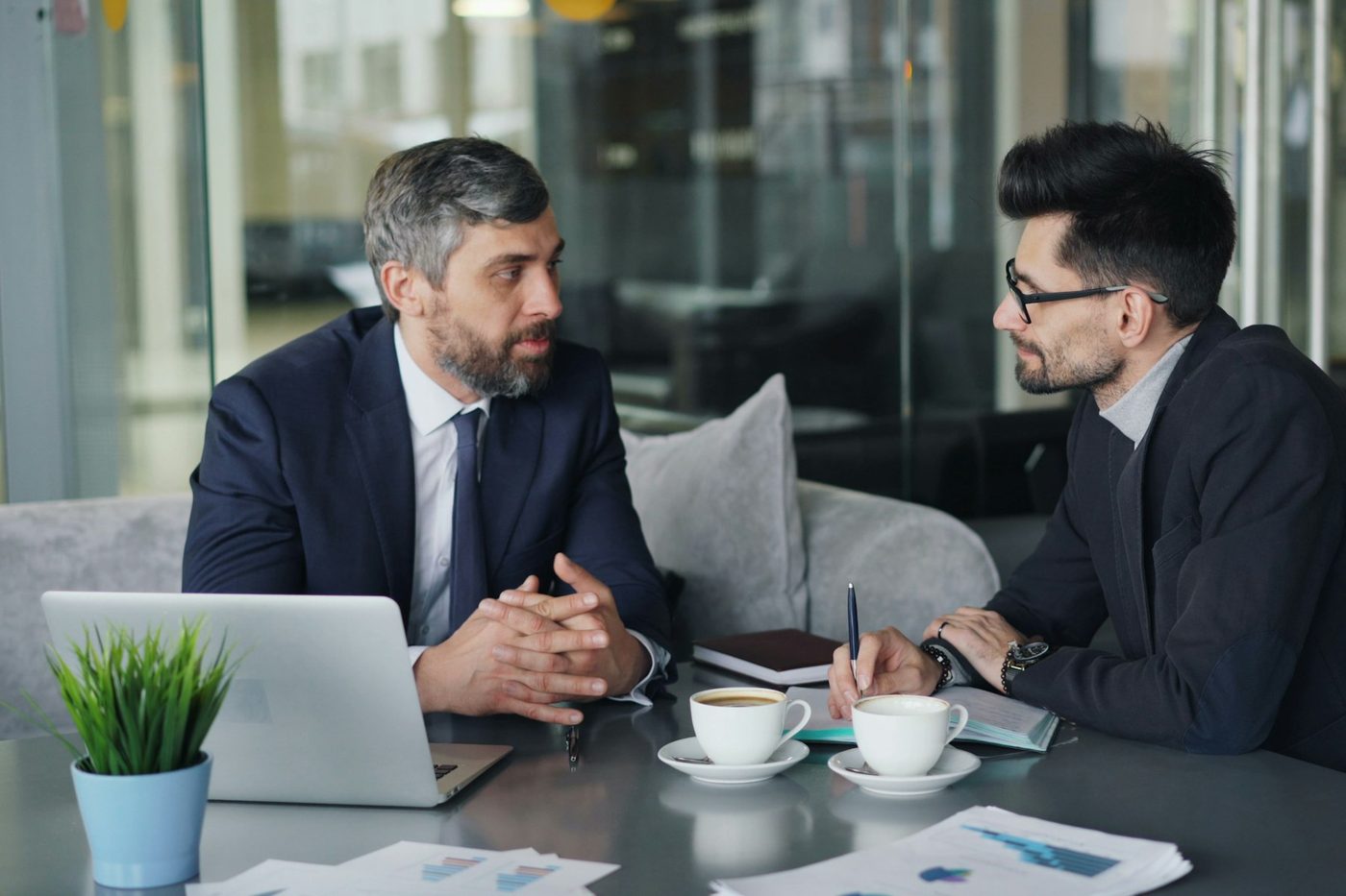 Two people in conversation across a table, with printed figures in front of them
