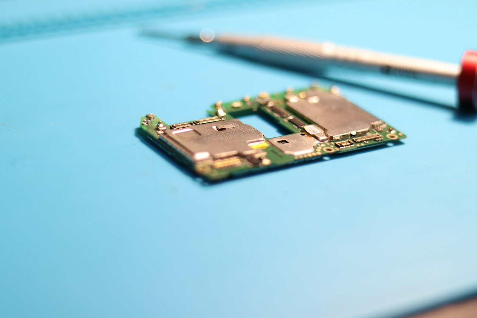 A phone circuit board being worked on with a screwdriver